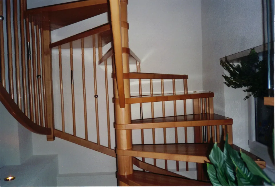 Wendeltreppe aus hellem Holz mit Stabgeländer und Mittelsäule